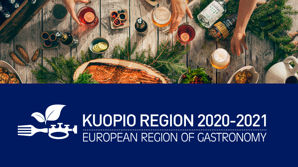 Kupio Region 2020-2021 logo, kuvassa myös loimulohta, erilaisia juomia ja lisukkeita puupöydällä.